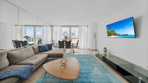 A modern living room with a sofa, coffee table, and a TV mounted on the wall. - Florida Sunrise Pool Hot Tub (Miami)