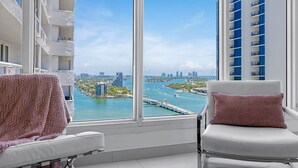 A room with a large window overlooking a marina and cityscape. - Highrise Charm (Miami)