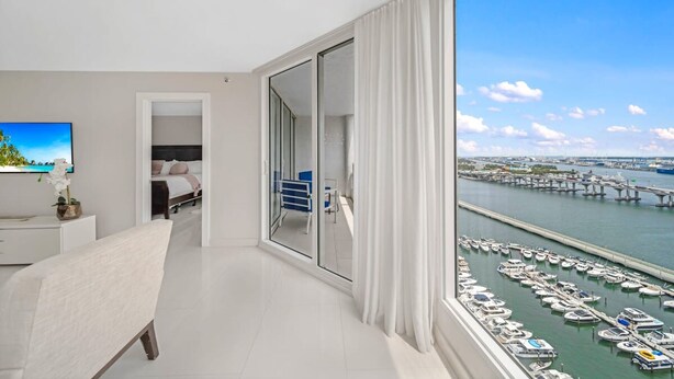 A modern hotel room with a large balcony, a view of a marina, and a dining area with a view of the water. - Azure Skies High Floor (Miami)