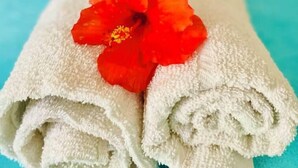 Un paio di asciugamani bianchi ordinatamente piegati con un fiore di ibisco rosso adagiato sopra.