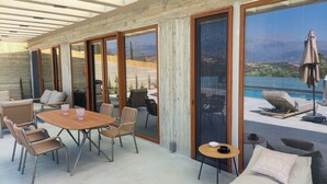 Un espacio lounge moderno al aire libre con una mesa de madera, sillas de mimbre y un sofá.