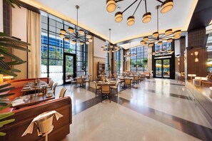 A spacious hotel lobby with multiple dining areas, large windows, and modern lighting fixtures. - Luxurious Miami Studio in DTW | Pool | Balcony (Miami)