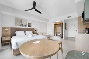 A modern hotel room with a bed, bedside tables, a round wooden table, a ceiling fan, and artwork on the wall. - Luxurious Miami Studio in DTW | Pool | Balcony (Miami)