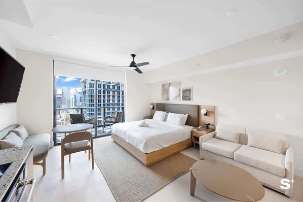 A modern hotel room with a large bed, a sofa, a dining table, and a balcony with a city view. - Luxurious Miami Studio in DTW | Pool | Balcony (Miami)