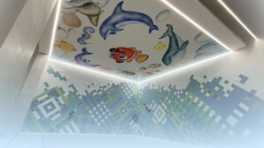 Un plafond orné d’une fresque colorée représentant des créatures marines et une vue d’une ville, stylisée en pixels.