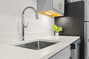 A modern kitchen with a stainless steel sink, a built-in dishwasher, and a black refrigerator.