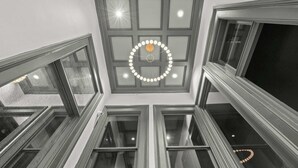 Une pièce aux hauts plafonds, dotée de nombreuses fenêtres et d’un luminaire central.