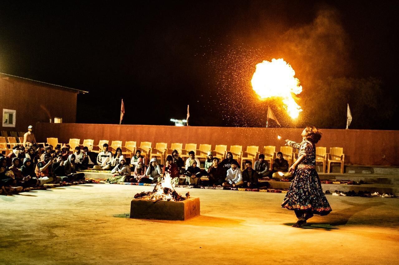 Une personne exécutant une danse avec le feu devant un public assis.
