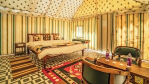 A tent-style room with a bed, a wooden table with chairs, and a patterned rug. - Tokyo Desert Camp (Jaisalmer)