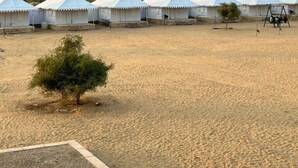 A row of white tents with a clear view of the desert landscape in the background. - Tokyo Desert Camp (Jaisalmer)