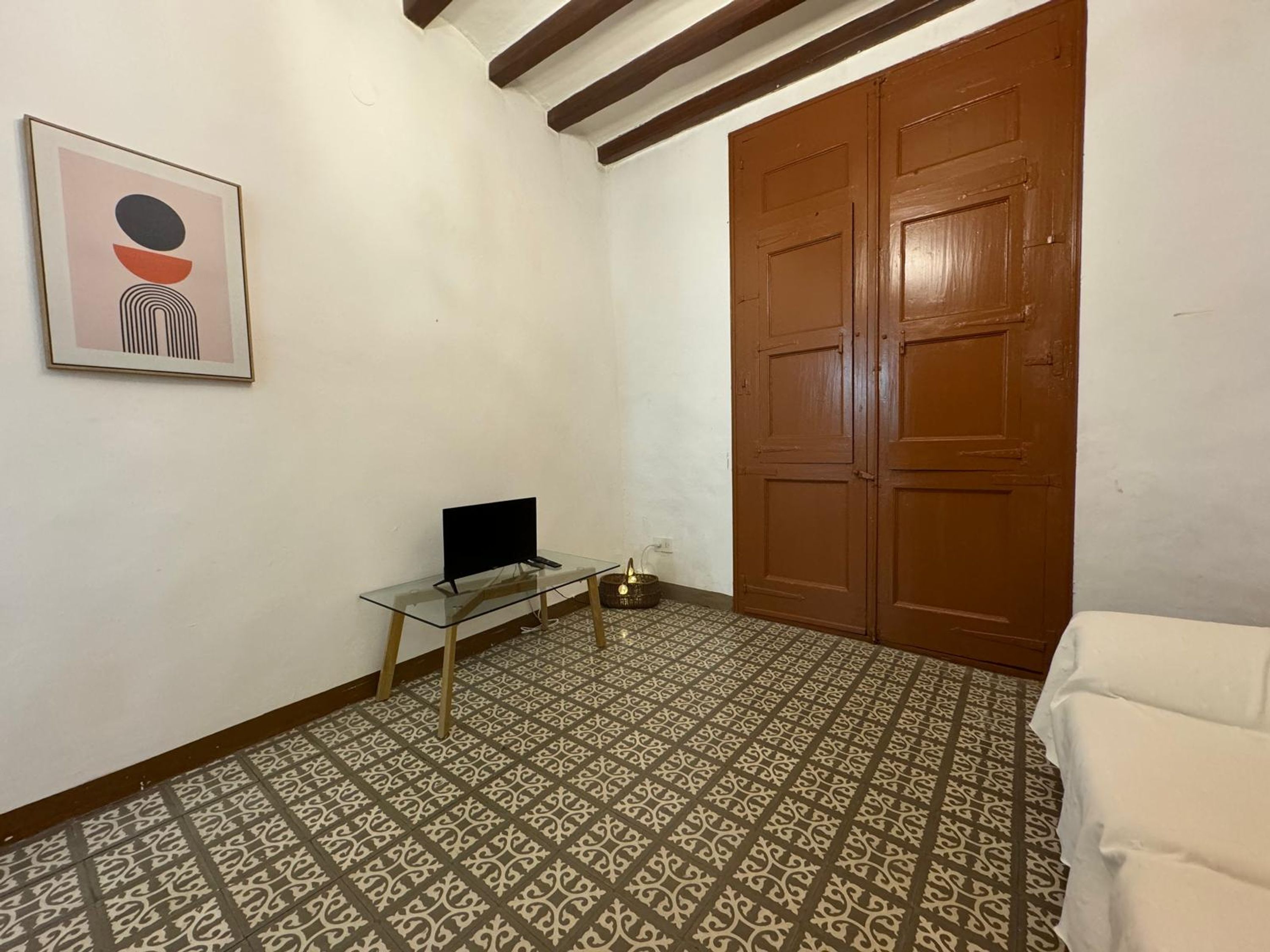 A room with a patterned floor, a desk with a computer, a door, and a framed picture on the wall.