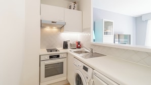 Een kleine keuken met een wasmachine, een broodrooster en een magnetron.