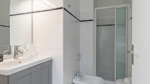 Een moderne badkamer met een wit wastafelmeubel, spiegel en douchecabine.