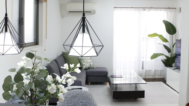 A modern living room with a sofa, a coffee table, and hanging pendant lights. - NEW OPEN 2 minutes walk from Higashi-Shinjuku Station (新宿区)