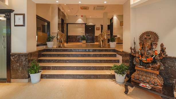 A hotel lobby with marble steps, potted plants, and a statue. - One Earth City Heart Amritsar (Amritsar)