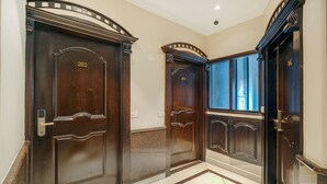 A hallway with three dark wooden doors, numbered 202, 203, and 204, leading to rooms. The floor has a patterned tile design. - One Earth City Heart Amritsar (Amritsar)