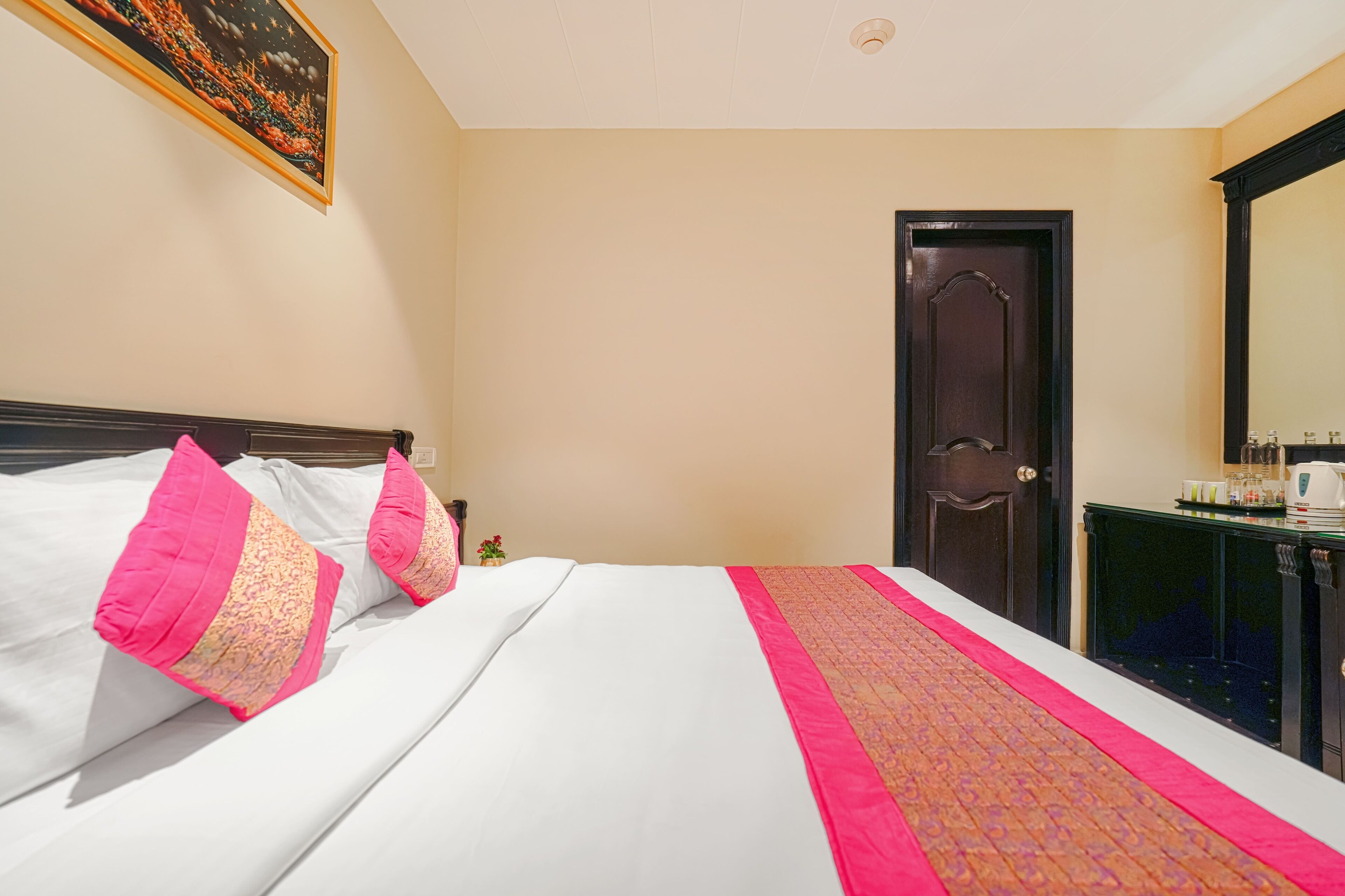 A hotel room with a bed, a nightstand, a door, and a mirror.
