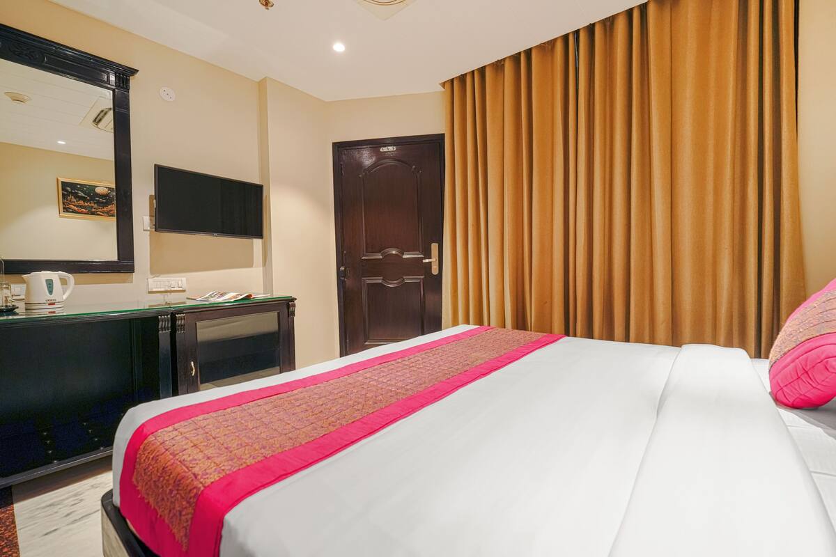 Een hotelkamer met een bed, een bureau, een televisie en een deur.