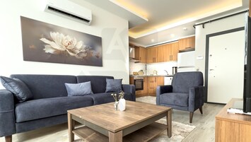 Apartamento Deluxe, balcón, vistas a la ciudad | Zona de estar | Televisión de 120 pulgadas con canales por satélite