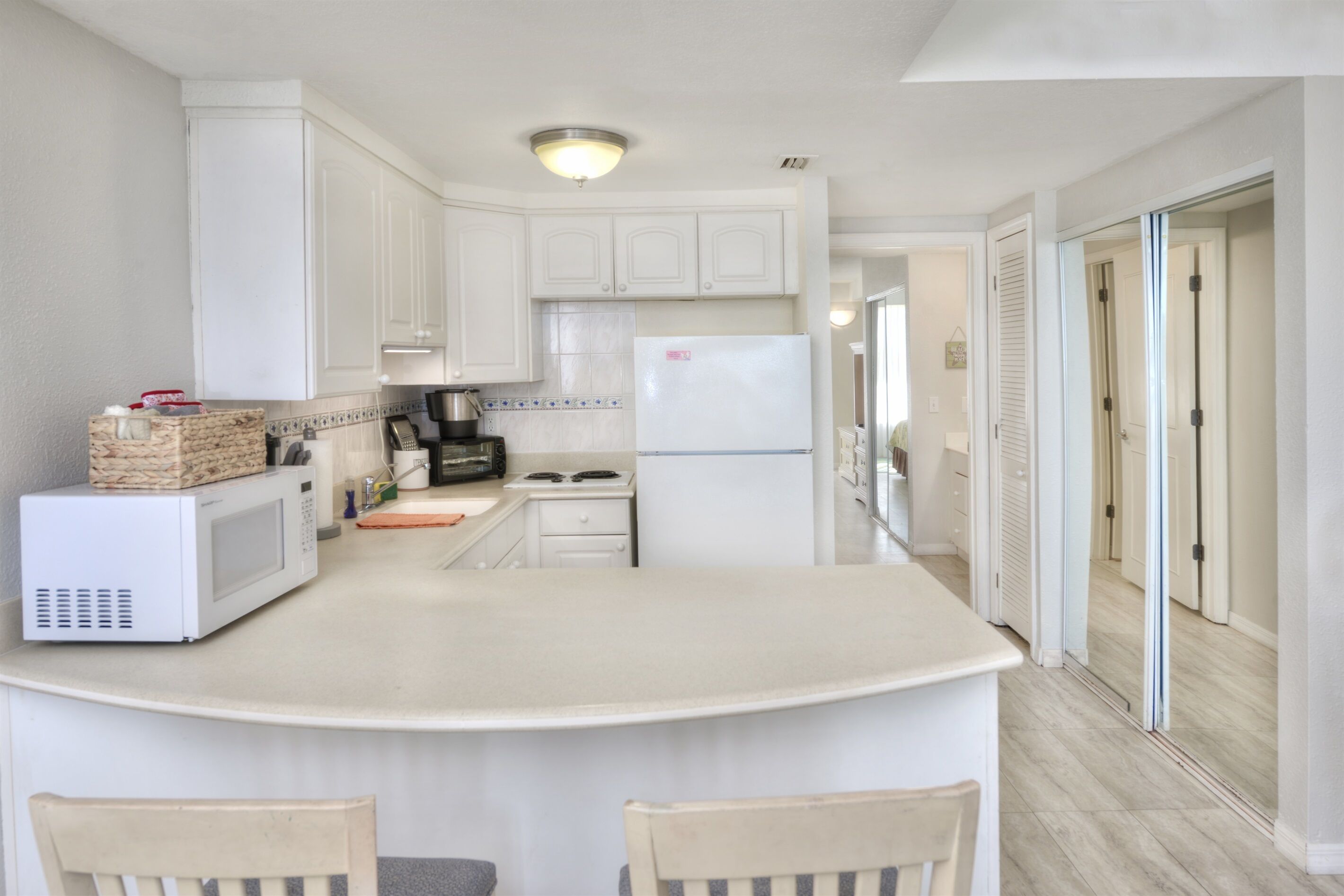 A kitchen with white cabinets, a microwave, a stove, and a refrigerator.