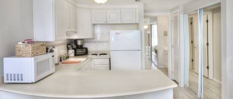 A kitchen with white cabinets, a microwave, a stove, and a refrigerator.