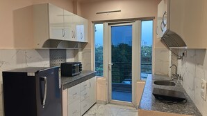 A modern kitchen with a refrigerator, microwave, and sink. - Solhouse Serviced Apartments Gurgaon (Gurugram)