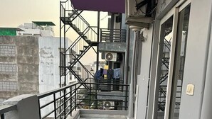 A narrow corridor with a marble floor, a purple ceiling, and a metal railing on one side. - Solhouse Serviced Apartments Gurgaon (Gurugram)