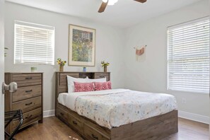 Ein Schlafzimmer mit einem hölzernen Bett, einem Schminktisch, einem Deckenventilator und einem Gemälde an der Wand.