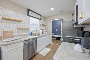A modern kitchen with white cabinetry, a herringbone tile backsplash, and a built-in oven.