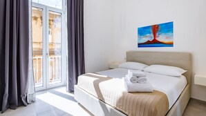 Une chambre d’hôtel avec un lit, un tableau et une vue sur un immeuble par la fenêtre.