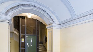 An arched hallway with a green door, marble flooring, and a staircase leading to an upper level. - Maison Vittorio Emanuele (Naples)