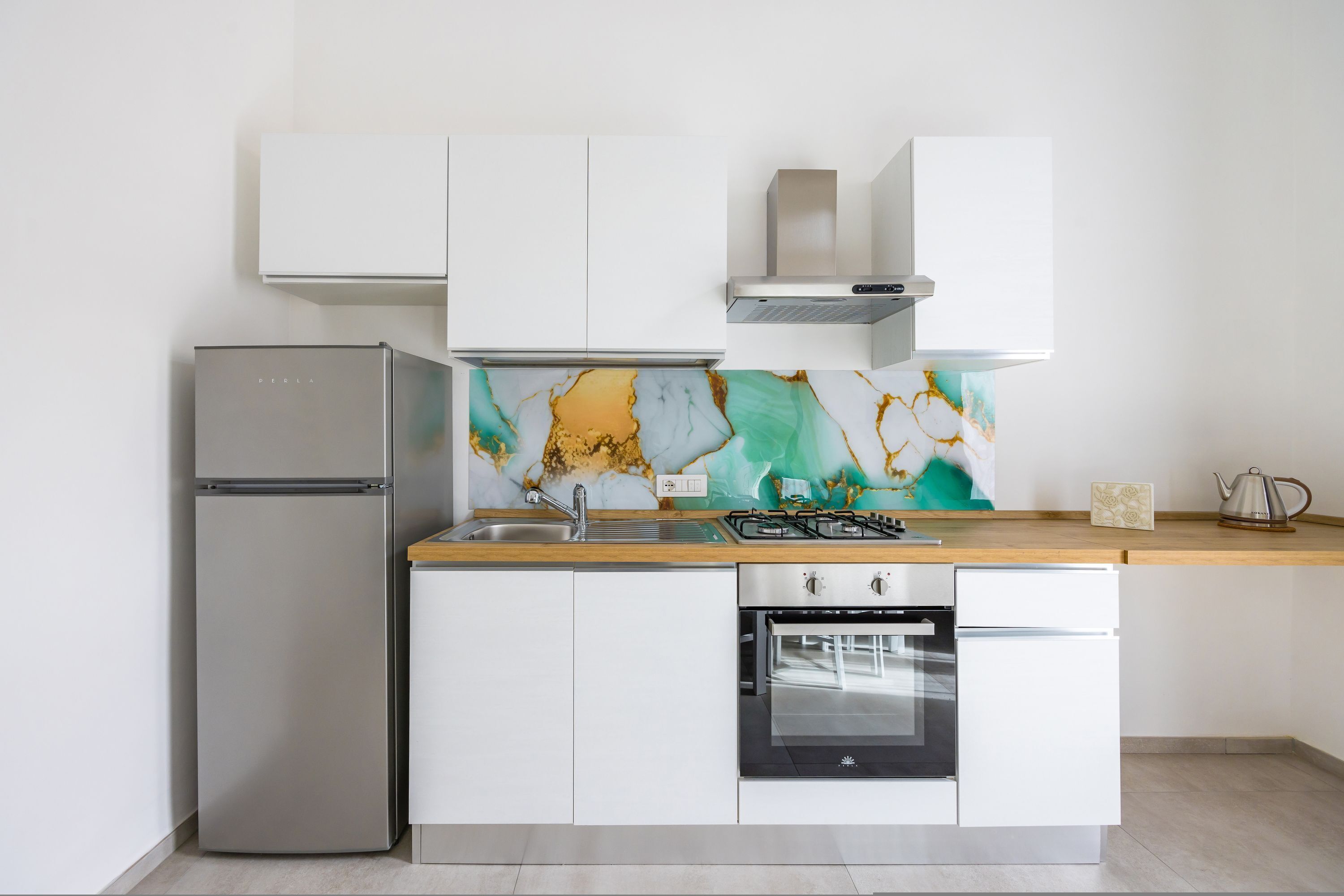 A modern kitchen with a stainless steel refrigerator, built-in oven, and a gas stove.