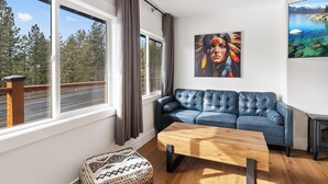 A modern living room with a blue sofa, a wooden coffee table, and a painting on the wall.