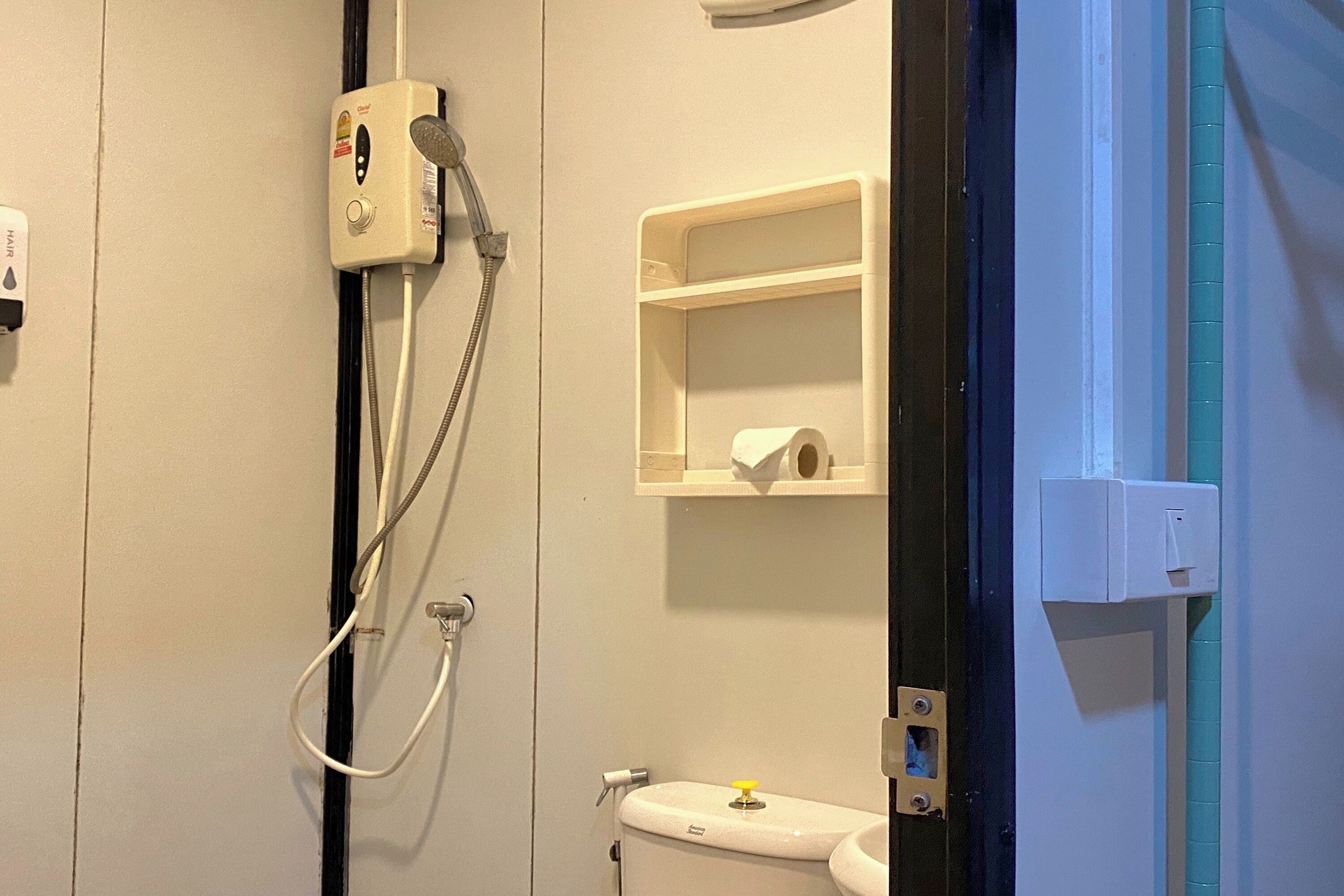 Ein Badezimmer mit Dusche, Toilette und Ablage für Toilettenartikel.