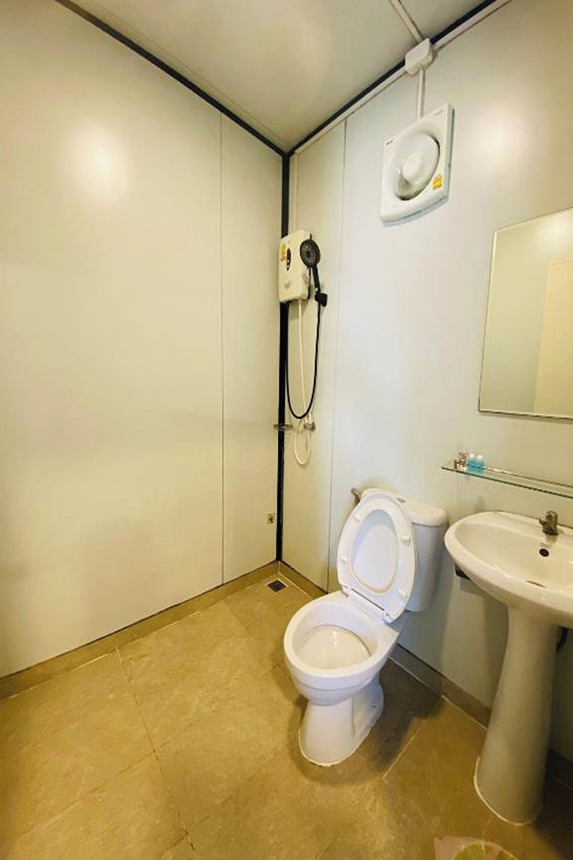 A small bathroom with a toilet, sink, and shower.