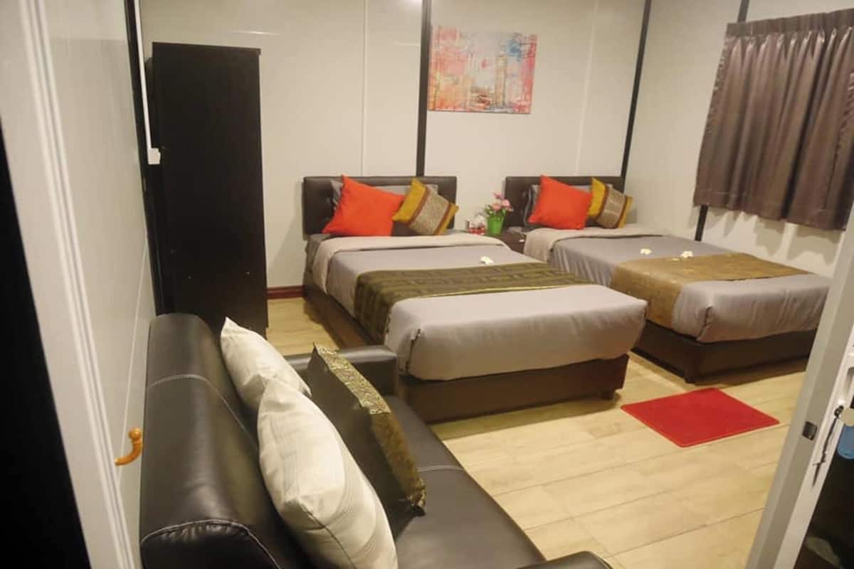 Hotellihuone, jossa on kaksi sänkyä, sohva ja punainen matto.