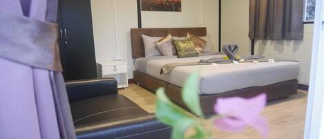 A hotel room with a bed, a nightstand, a wardrobe, and a cityscape painting on the wall.