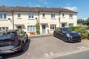 A residential building with a paved driveway and two parked cars.