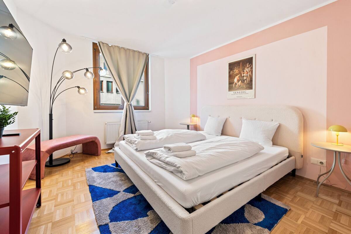 Un dormitorio ordenado con cama, mesitas de noche, un escritorio y una silla.
