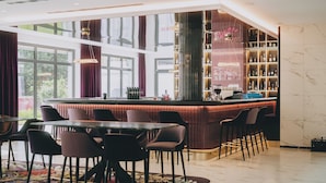 A bar area with a high bar counter, seating, and a view of the outdoors. - Grand Elisabeth (Bad Ischl)