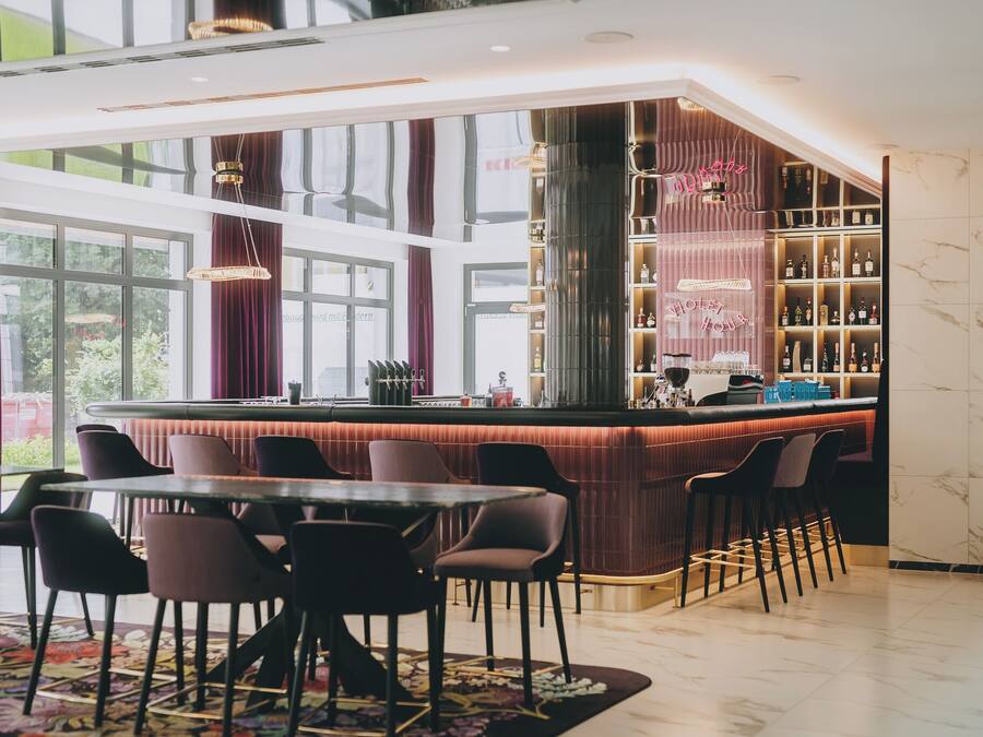 A bar area with a high bar counter, seating, and a view of the outdoors.