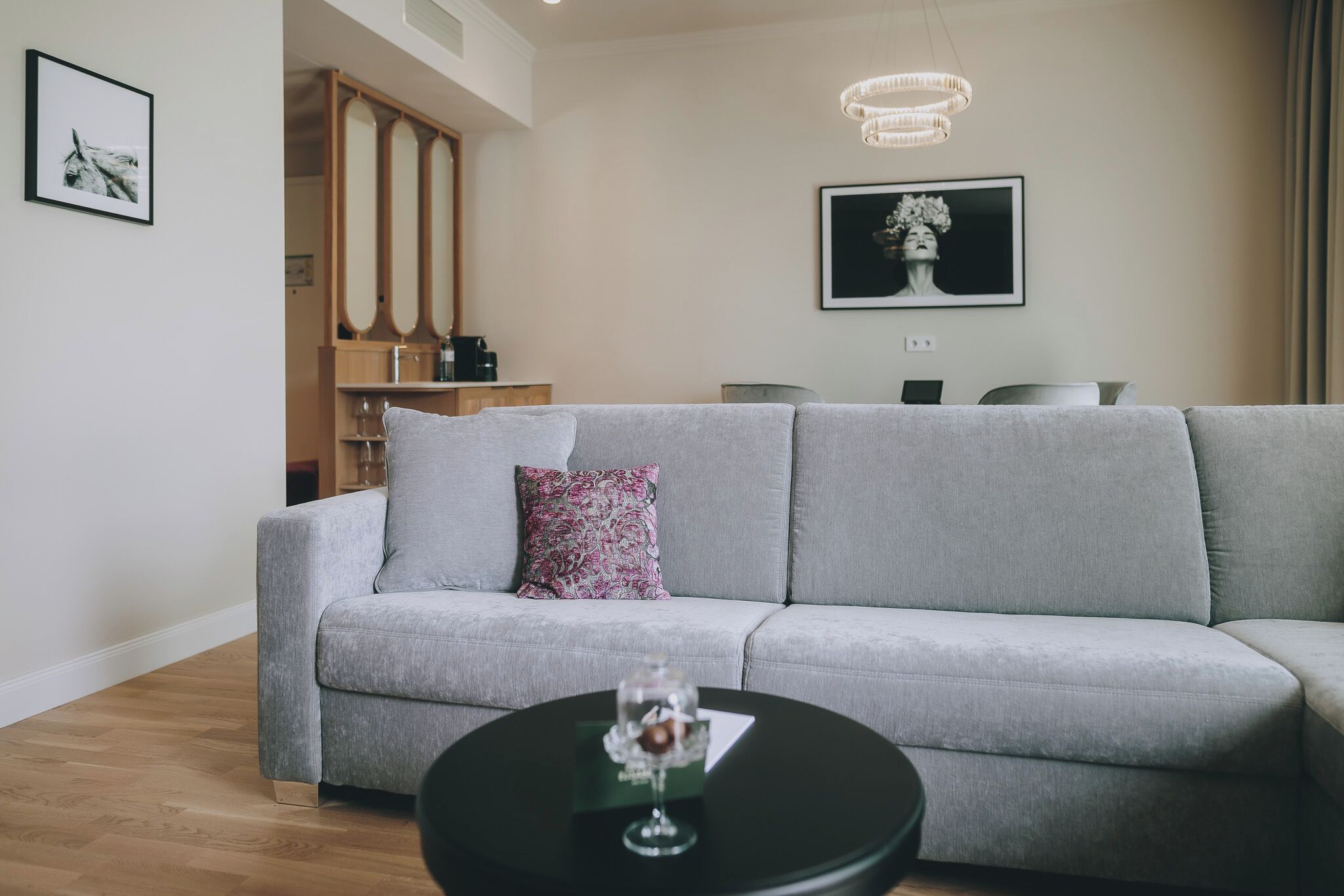 A modern living room with a grey sofa, a black coffee table, and a framed artwork on the wall.