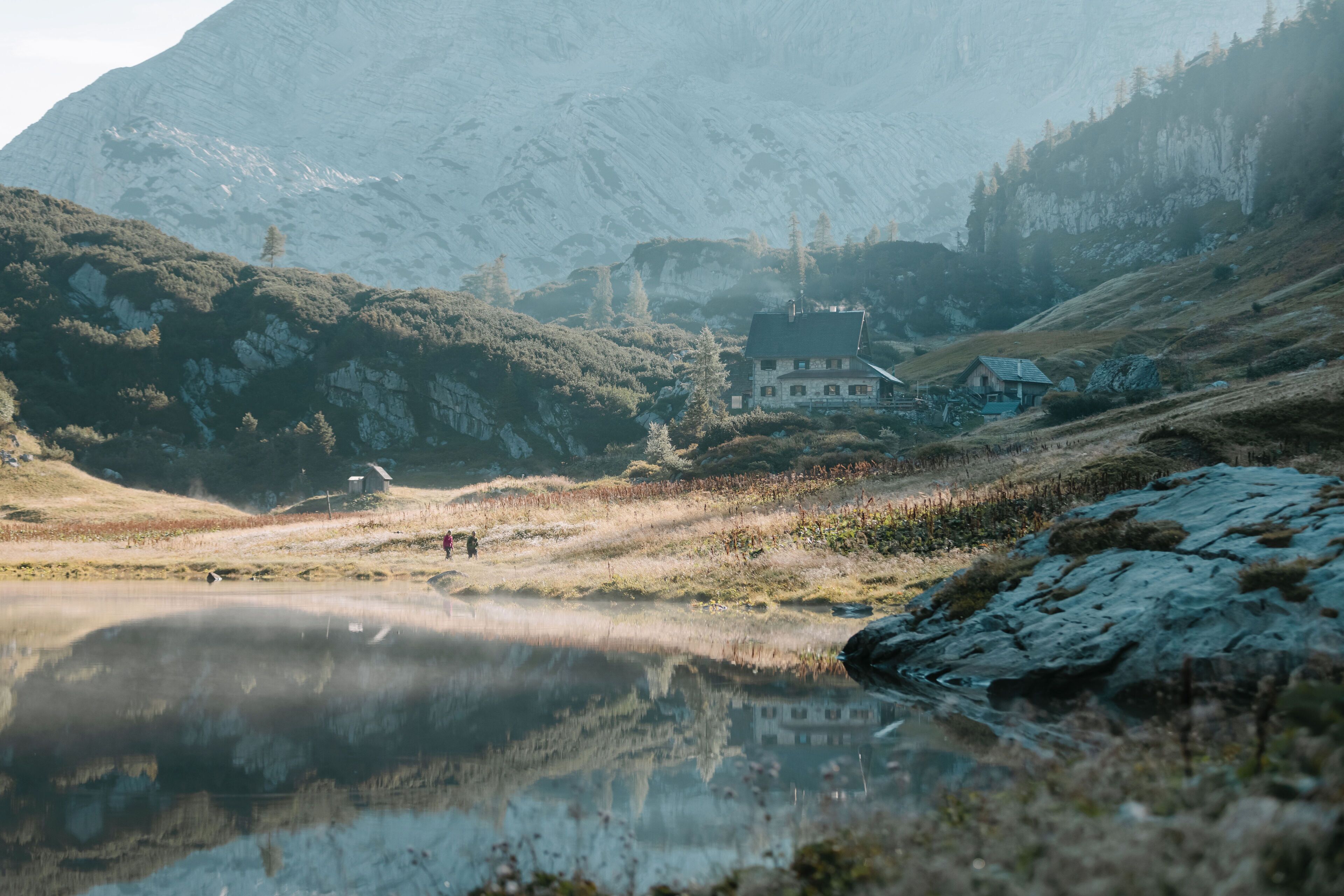 A mountain landscape with a house and a pond.