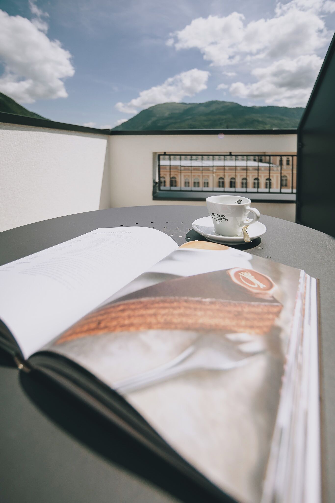 A table with a book, a cup of coffee, and a magazine.