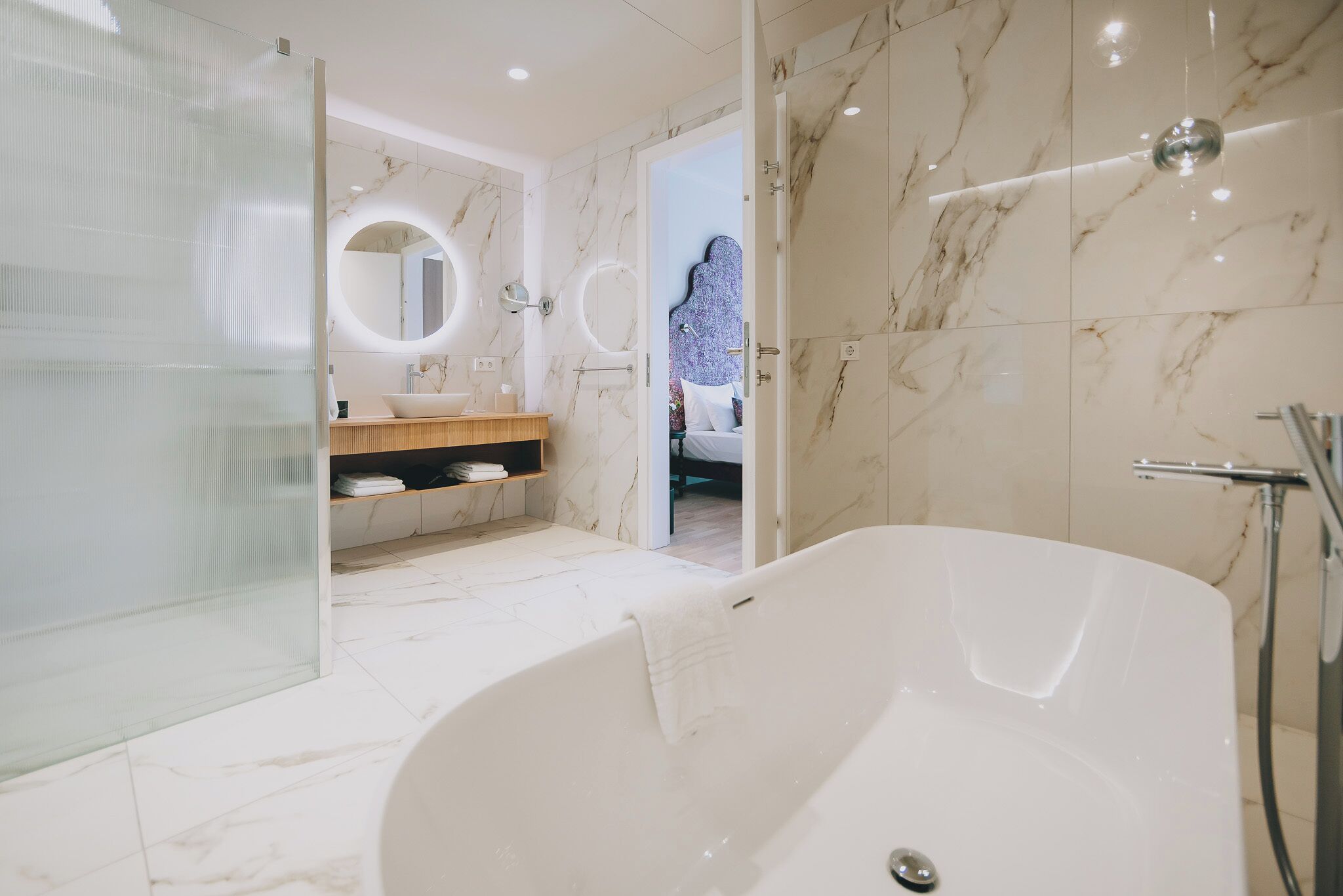 Une salle de bain moderne dotée d’une grande baignoire, d’une douche à parois de verre et d’un meuble-lavabo avec un plan de travail en marbre.