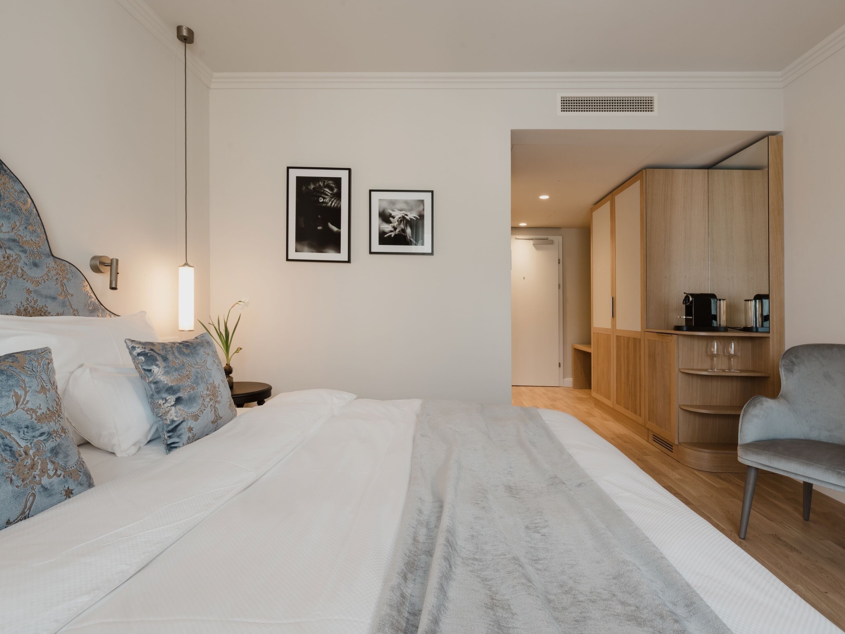 Un dormitorio con una cama, mesita de noche, lámpara y dos cuadros en la pared.