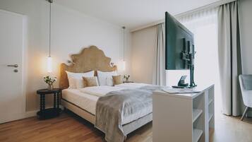 Una habitación de hotel moderna con una cama grande, un escritorio con televisión de pantalla plana y una silla.