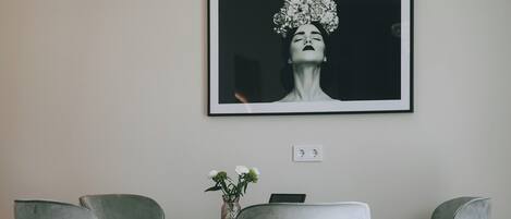 A modern living room with a grey sofa, a decorative pillow, a framed artwork on the wall, and a chandelier.