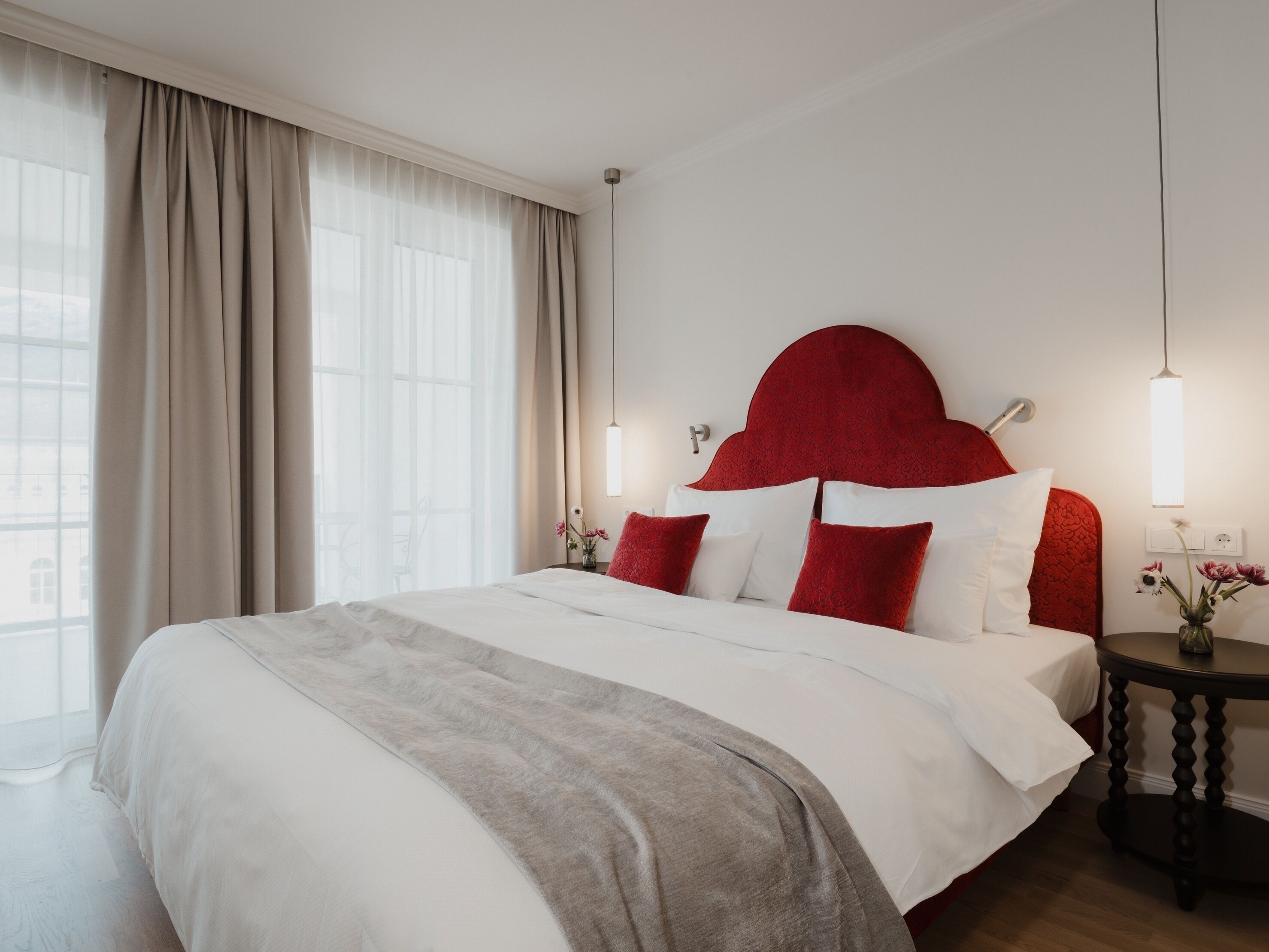 Ein Hotelzimmer mit einem großen Bett, einem roten Kopfteil und zwei Nachttischlampen.