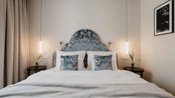 A neatly made bed with a blue headboard, two bedside tables with lamps, and a framed picture on the wall.
